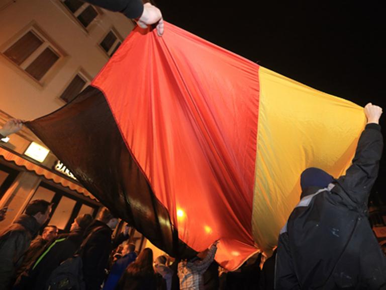 Anhänger der islamkritischen Bewegung Magida tragen während ihres Spazierganges eine Deutschland-Fahne.