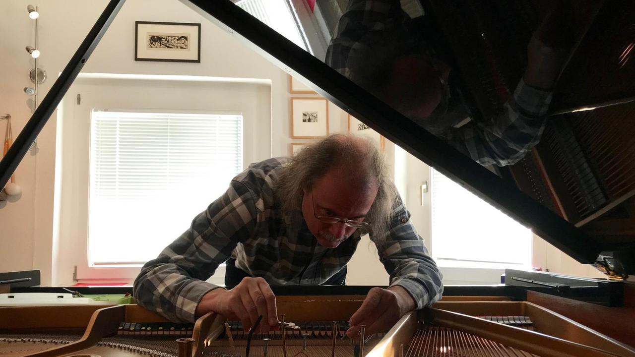 Der Pianist und Komponist Steffen Schleiermacher präpariert ein Klavier.