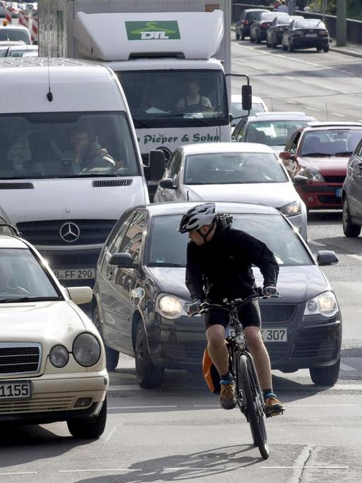 Ein Radfahrer schlängelt sich auf einer stark befahrenen Straße durch den Autoverkehr