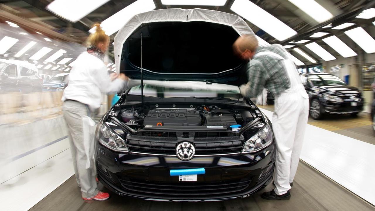 Ein Golf VII steht am 25.02.2013 im Volkswagen-Werk in Wolfsburg (Niedersachsen), zwei Arbeiter blicken in den Motorraum.
