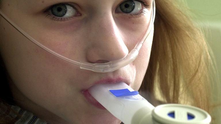 Ein an Mukoviszidose erkranktes Mädchen inhaliert mit Kochsalz versetzte Dämpfe.
