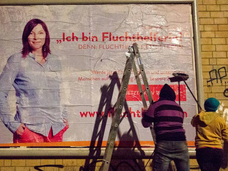 Peng-Aktivisten plakatieren in der Nähe der Berliner Ausländerbehöre ein Plakat mit der Aufschrift: "Ich bin Fluchthelferin!" Am selben Tag startete eine Kampagne für zivilen Ungehorsam, in dem die Aktivisten Urlauber zur Fluchthilfe auffordern.