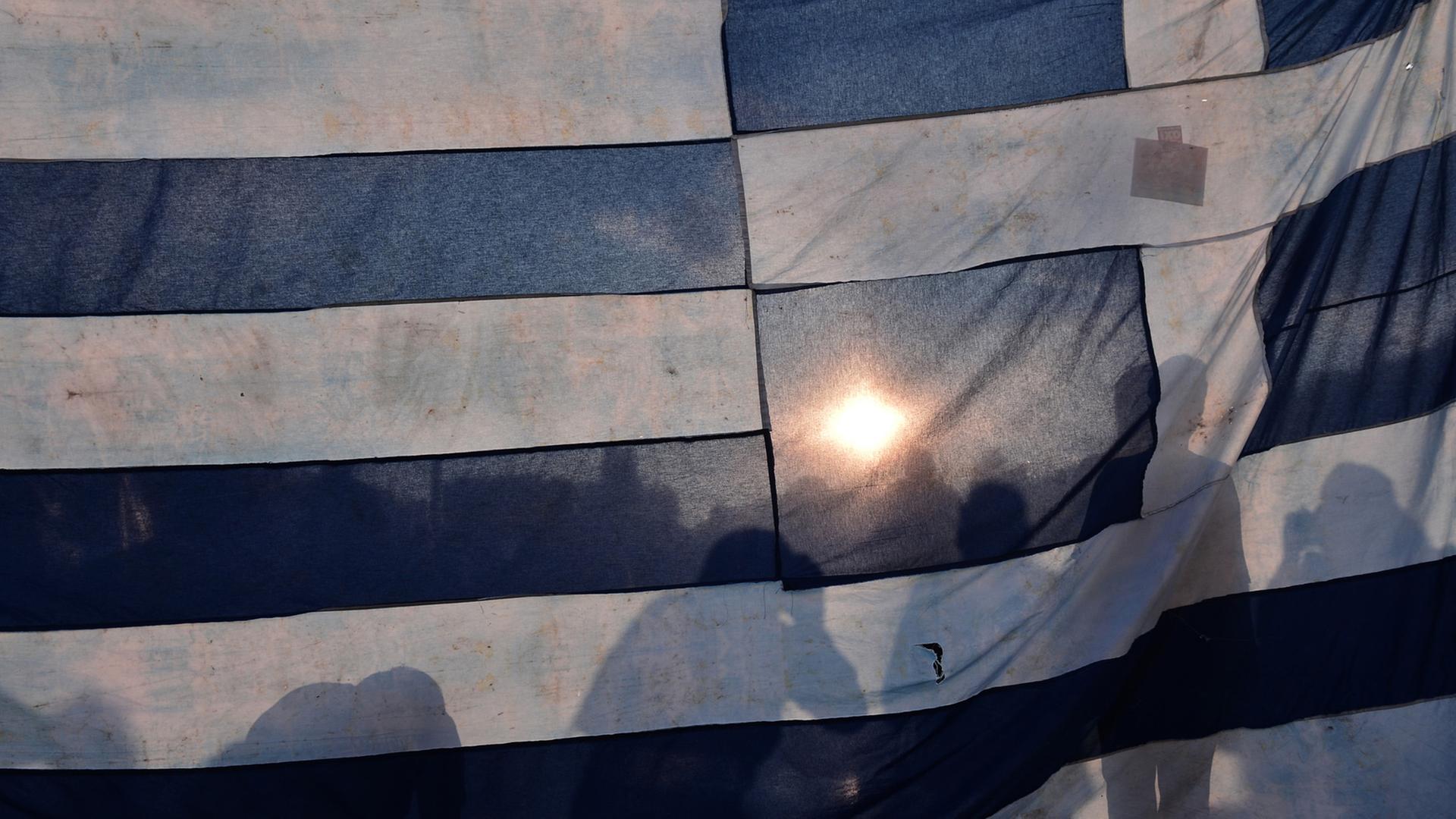 Demonstranten hinter einer griechischen Flagge in Athen