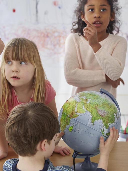 Diskutierende Kinder um einen Tisch, mit einem Globus.