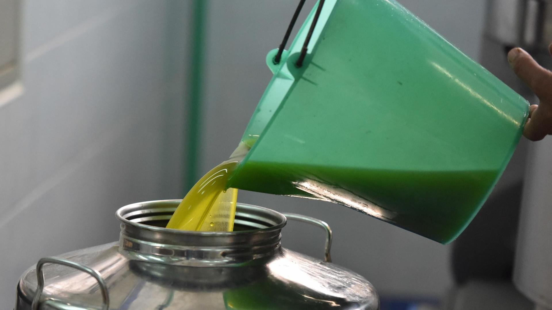 Olivenöl wird aus einem Behälter in einen größeren gegossen.