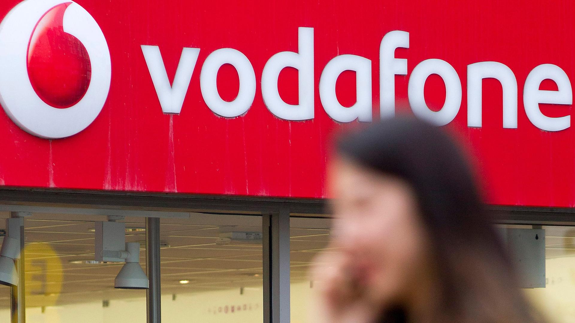 Frau geht telefonierend an einem Vodafone-Shop in London vorbei.