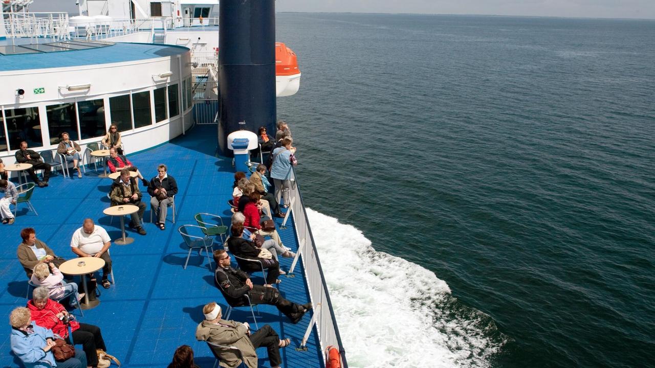 Passagiere sitzen am Sonntag an Deck einer Fähre, die den Fehmarnbelt auf der Ostsee zwischen Deutschland und Dänemark kreuzt.