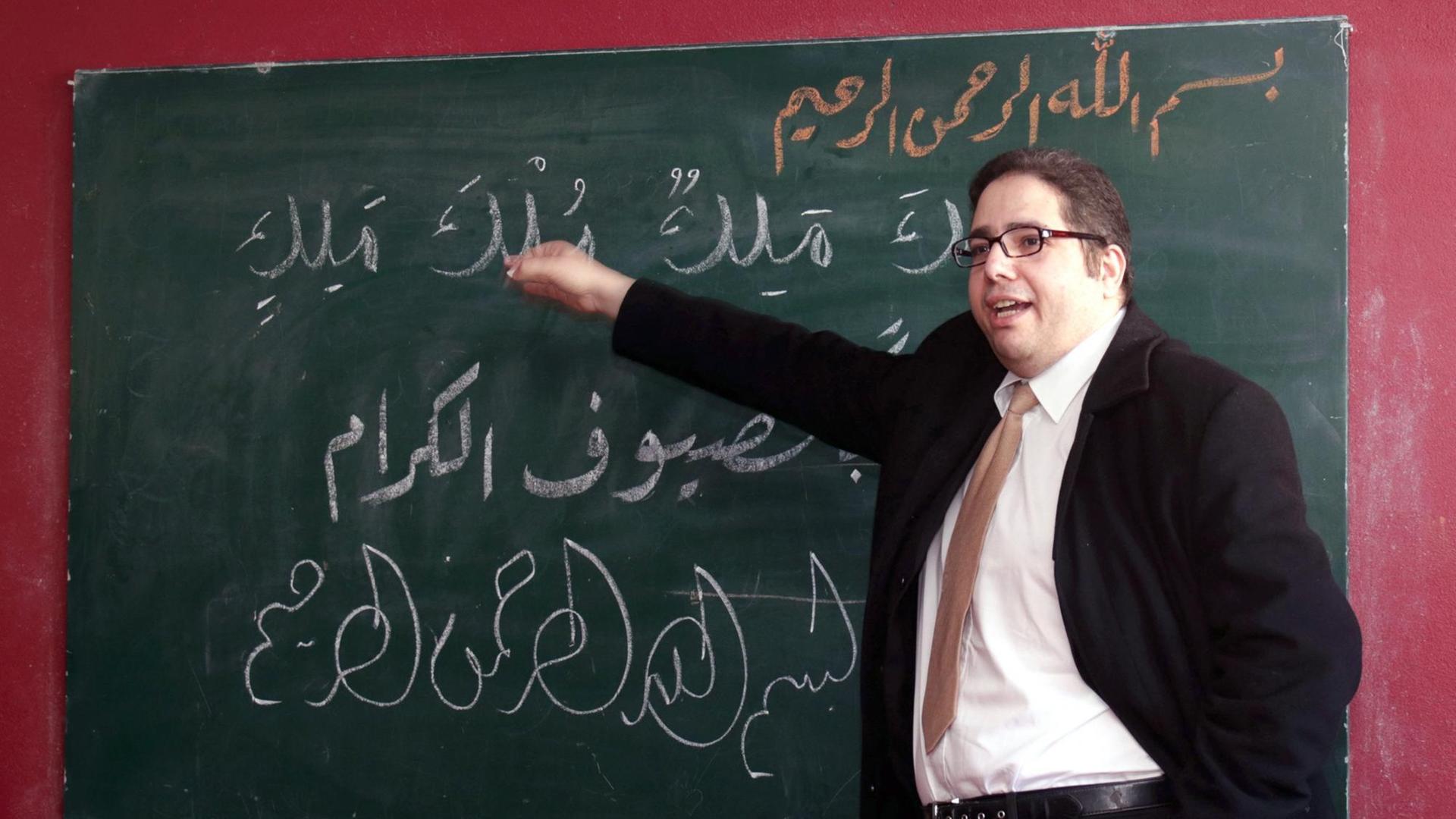 Abdassamad El Yazidi schreibt im islamischen Kulturzentrum Halle/Saale arabische Schriftzeichen an eine Wandtafel.