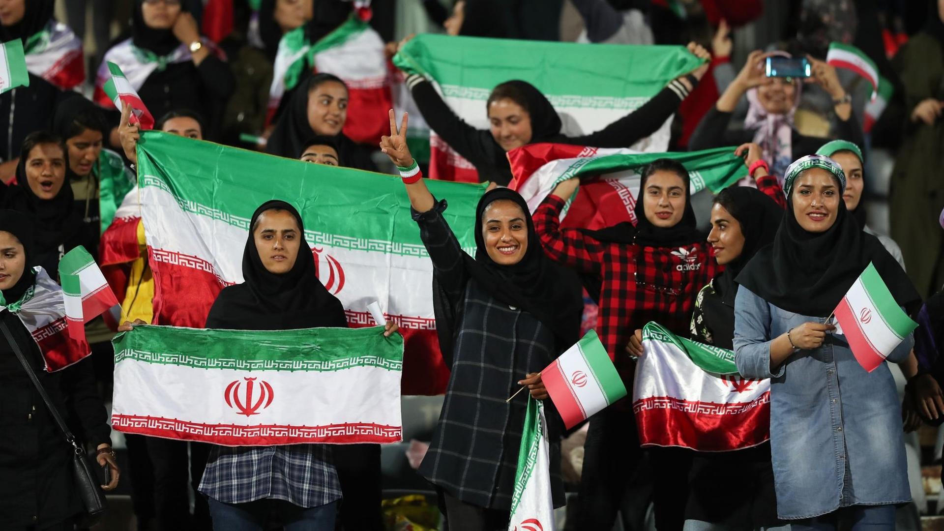 Iranische Frauen schwenken während des Spiels gegen Bolivien Nationalflaggen auf der Tribüne.
