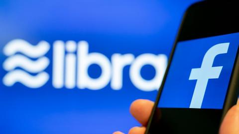 Ein Smartphone mit Facebook-App vor einem Libra-Logo.
