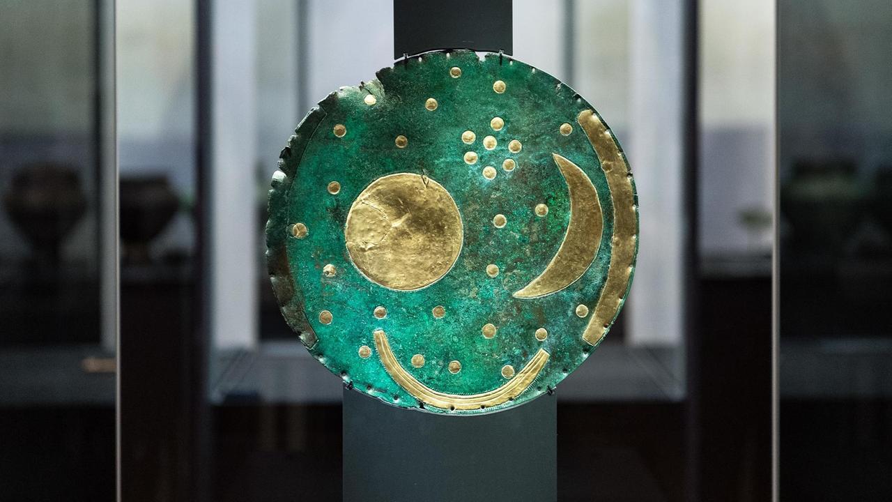 Eine antike grüne Scheibe mit Sternsymbolen steht in einer Vitrine.