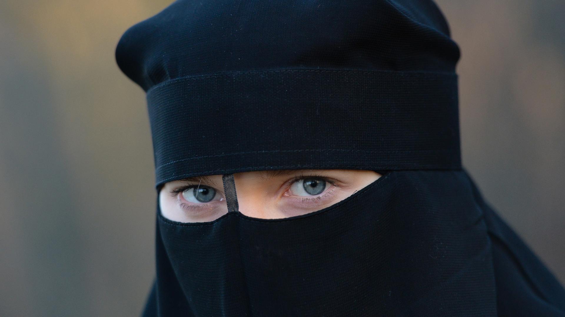 Eine Frau mit blauen Augen hinter einem schwarzen Niqab.