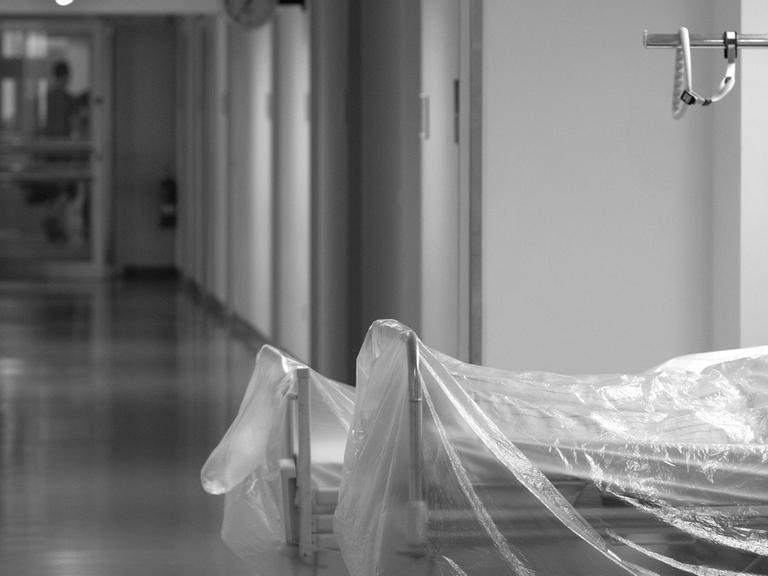 Zwei mit durchsichtiger Folie überzogene Krankenhausbetten stehen auf einem Krankenhausflur.