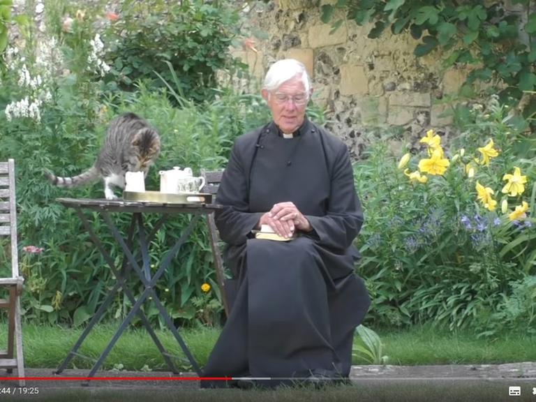 Screenshot des Youtube-Videos "Morning Prayer" vom 6. Juli 2020, erschienen auf den Kanal "Canterbury Cathedral". Im Ausschnitt sind Dekan Robert Willis und die Katze "Tiger" im Garten zu sehen.