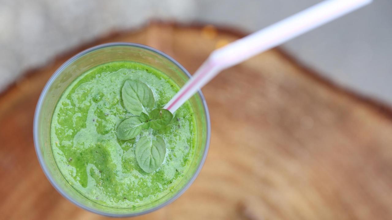 Ein grüner Smoothie in einem Glas mit Trinkhalm.
