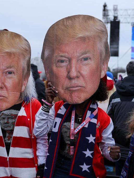 Mehrere Protestierende mit Trump-Masken stehen nahe dem Weißen Haus.