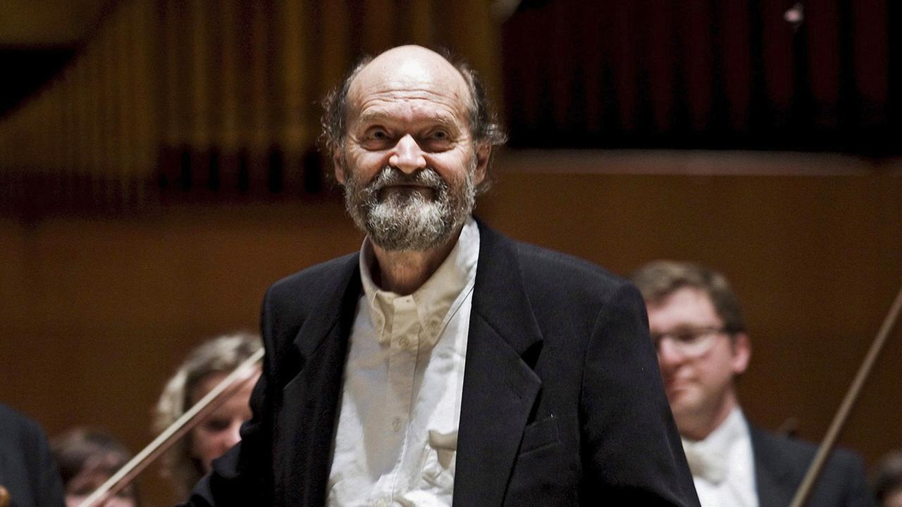 Der estnische Komponist Arvo Pärt im Jahr 2008, im Hintegrund die Musiker eines Sinfonie-Orchesters.
