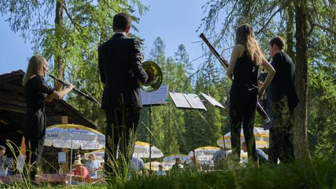 Musikerinnen und Musiker stehen beim Davos Festival 2020 unter Bäumen vor Publikum auf einer Wiese.
