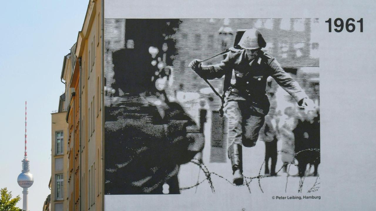 Abbildung des legendären Fotos von Peter Leibing an einer Hauswand in der Bernauer Strasse: Der Soldat Hans Conrad Schumann springt 1961 über den Stacheldraht.