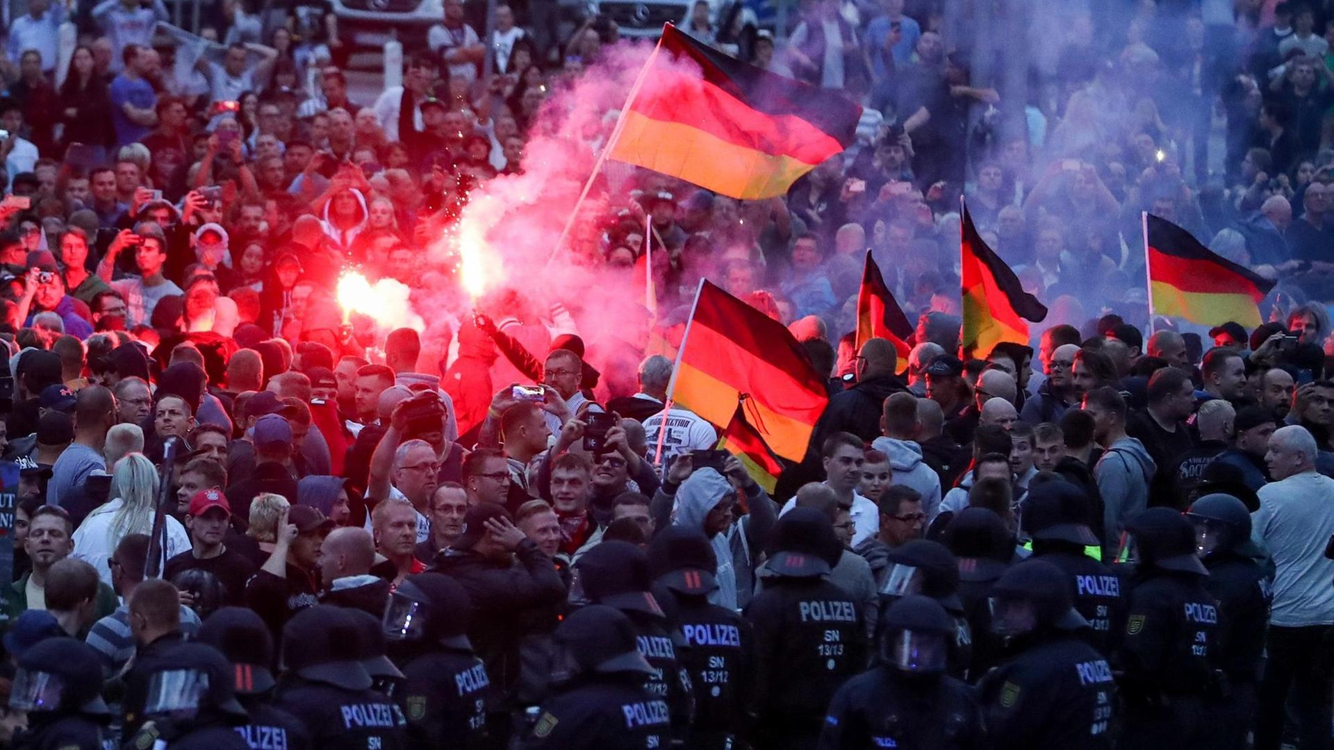 Chemnitz: Demonstranten der rechten Szene zünden Pyrotechnik und schwenken Deutschlandfahnen. Nach einem Streit war in der Innenstadt von Chemnitz ein 35-jähriger Mann erstochen worden. Die Tat war Anlass für spontane Demonstrationen, bei denen es auch zu Jagdszenen und Gewaltausbrüchen kam.