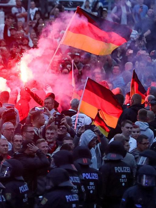 Chemnitz: Demonstranten der rechten Szene zünden Pyrotechnik und schwenken Deutschlandfahnen. Nach einem Streit war in der Innenstadt von Chemnitz ein 35-jähriger Mann erstochen worden. Die Tat war Anlass für spontane Demonstrationen, bei denen es auch zu Jagdszenen und Gewaltausbrüchen kam.