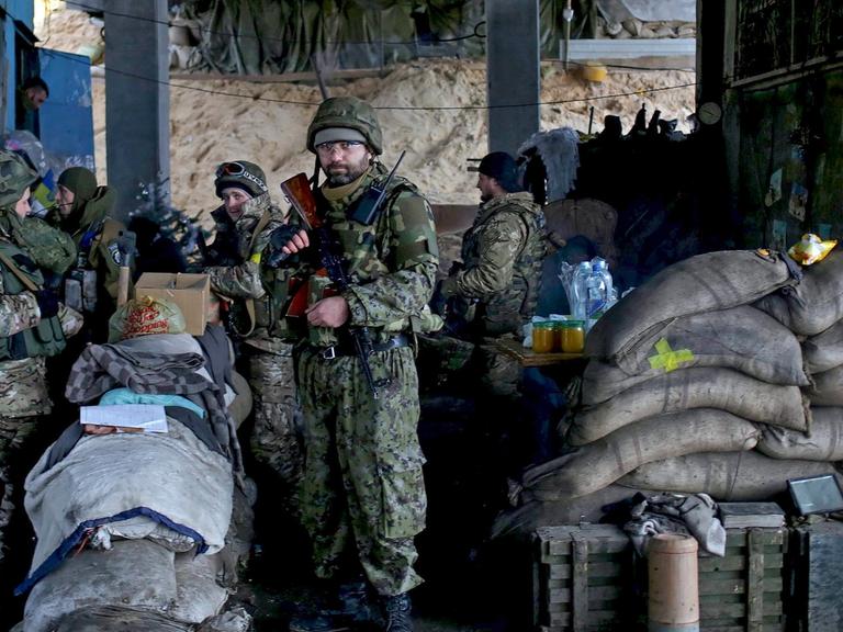 Eine Gruppe von ukrainischen Soldaten steht bewaffnet und mit Sandsäcken gesichert unter einer Brücke.