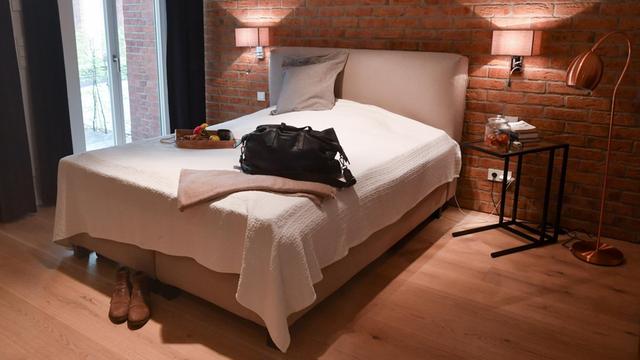 Ein Zimmer mit einem Bett. Auf dem Bett steht eine Reise-Tasche.