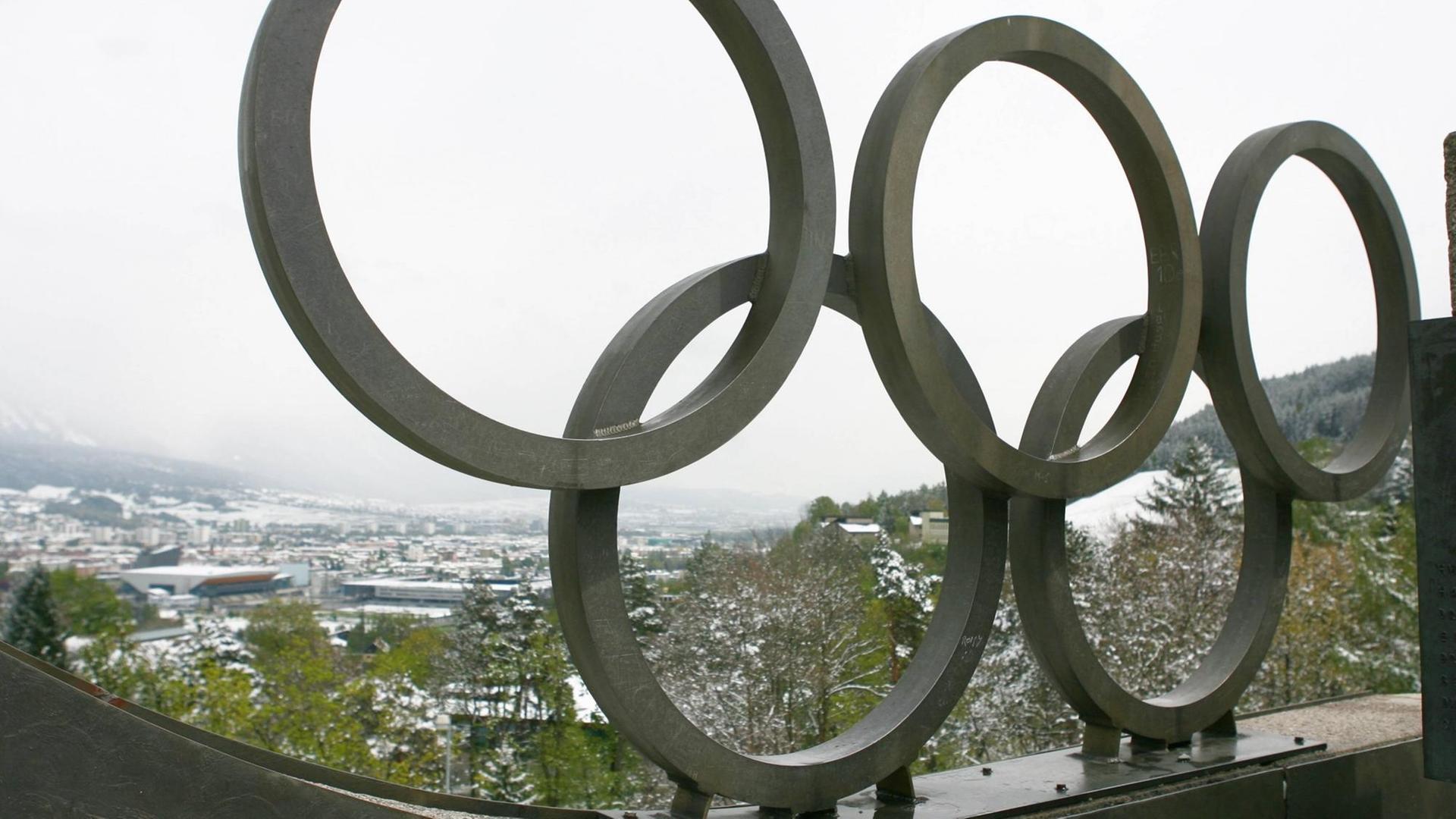 Großes Olympia-Logo aus Metall, im Hintergrund Stadt Innsbruck in Österreich