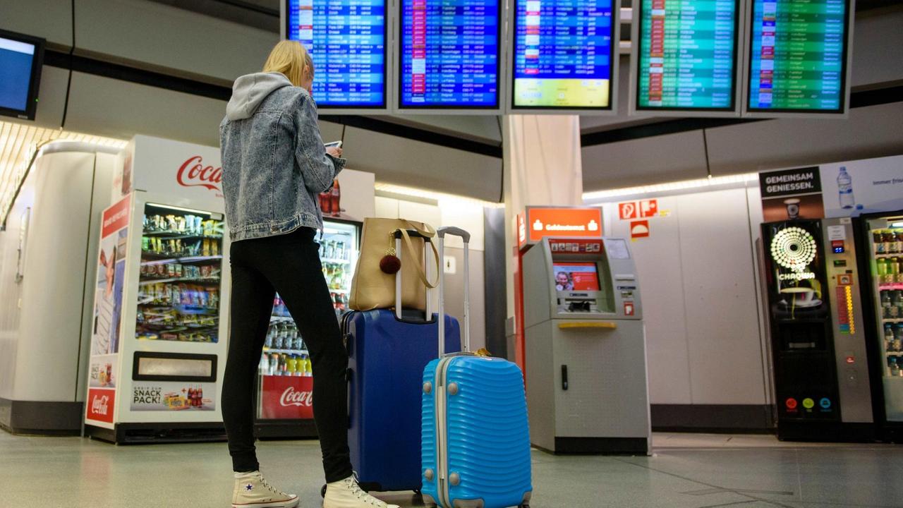 Eine Reisende steht am 10.03.2017 mit zwei Rollkoffern vor einer Anzeigentafel im Terminal des Flughafen Tegel in Berlin. Die Gewerkschaft Verdi hatte die rund 2000 Beschäftigten des Bodenpersonals zum Streik aufgerufen.