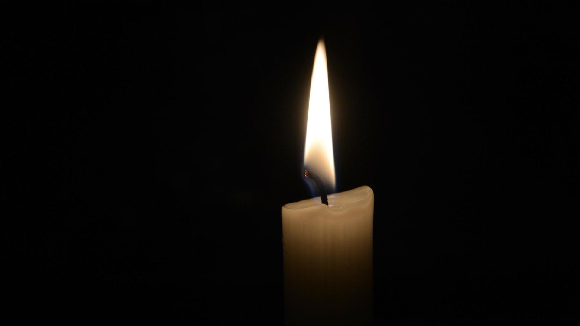 Eine Kerzenflamme in der Dunkelheit.