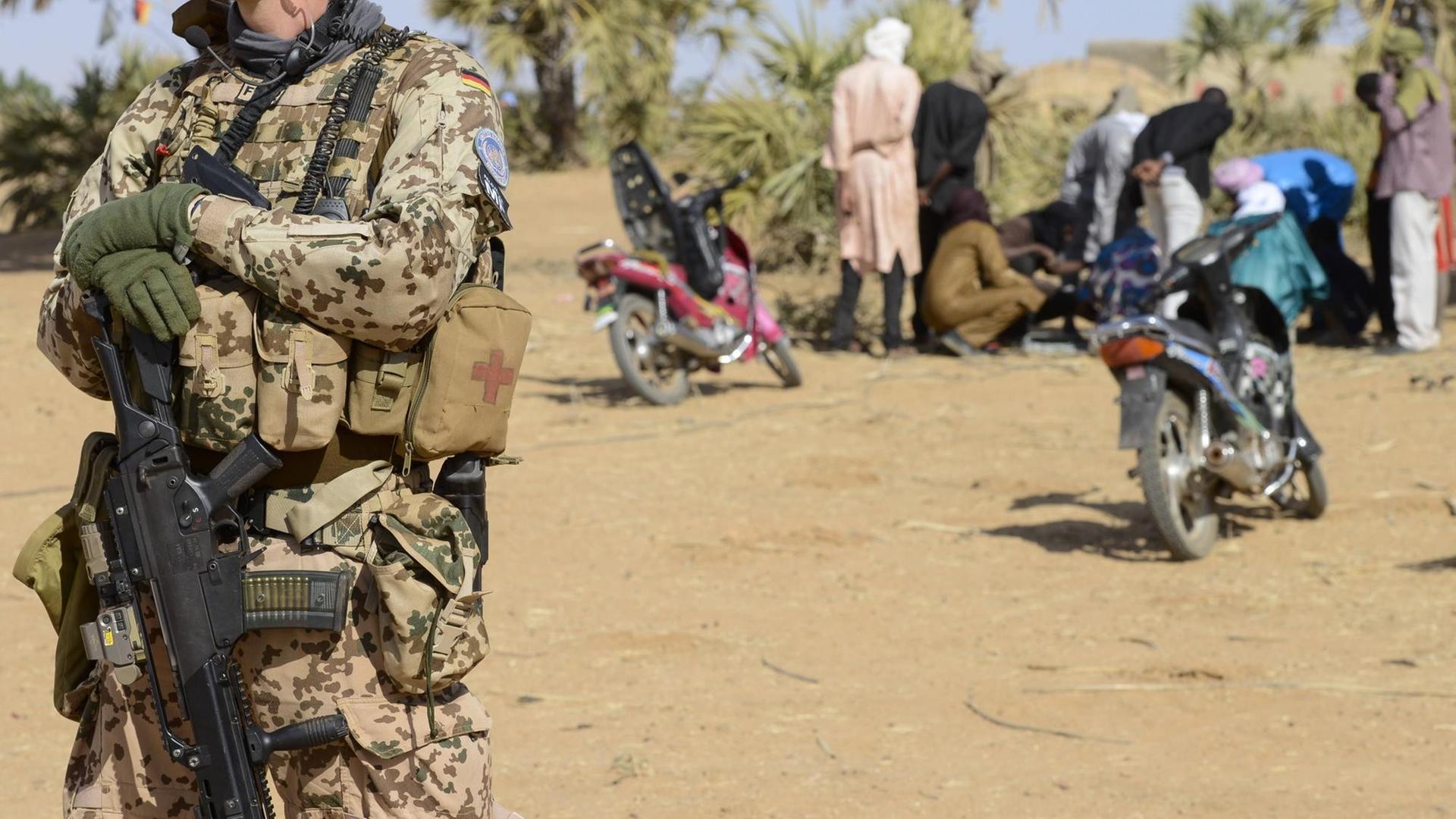 Ein deutscher Soldat der UN-Mission in Mali, im Hintergrund Einheimische