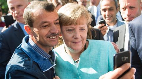 Bundeskanzlerin Angela Merkel posiert mit einem Flüchtling in einer Erstaufnahmeeinrichtung in Berlin für ein Selfie.
