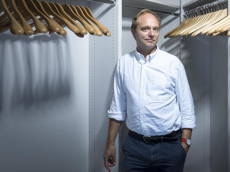 Prof. Dr. Frank Trentmann steht in einem begehbaren Kleiderschrank voller leerer Kleiderbügel.