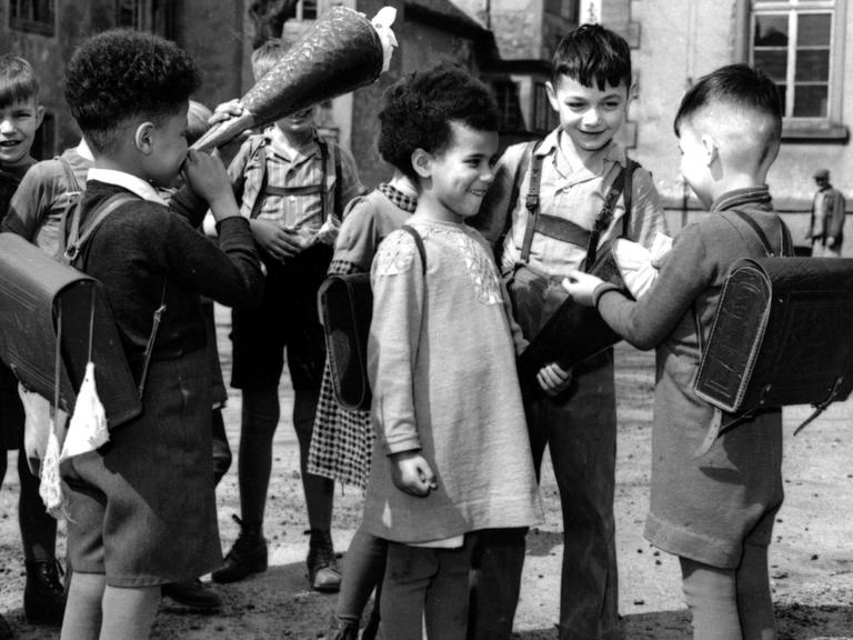 Undatierte Aufnahme: Auf dem Schulhof unterhalten sich zwei Besatzungskinder mit ihren Schulkameraden