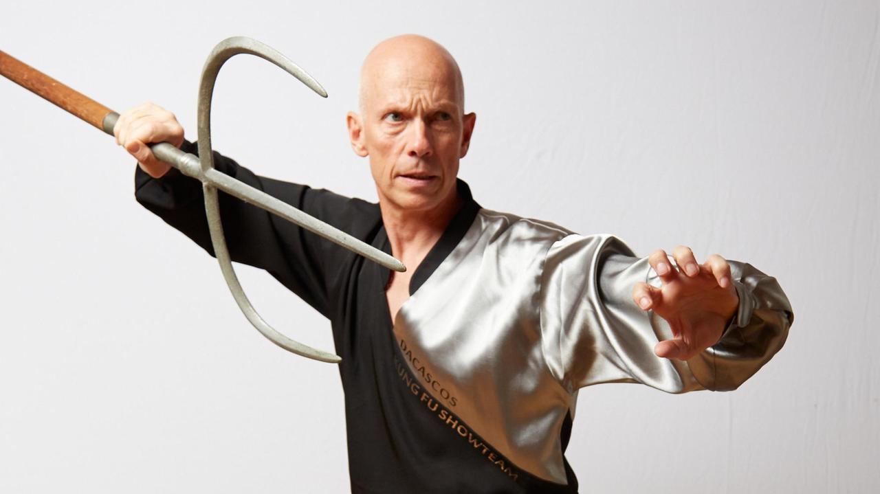 Christian Wulf trainiert in Kung Fu Kleidung mit einer Waffe die an eine Gabel erinnert