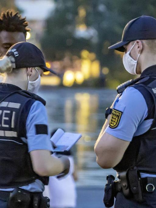Zwei Polizisten kontrollieren eine Person während der Krawalle in Stuttgart.
