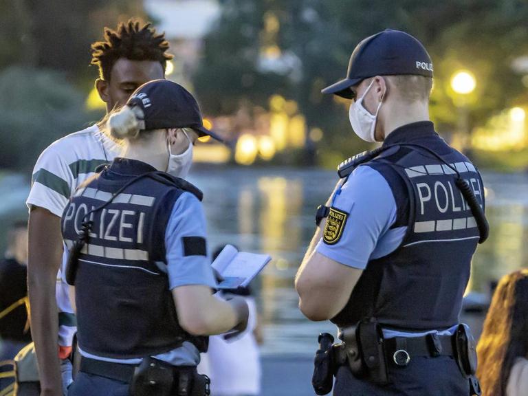 Zwei Polizisten kontrollieren eine Person während der Krawalle in Stuttgart.