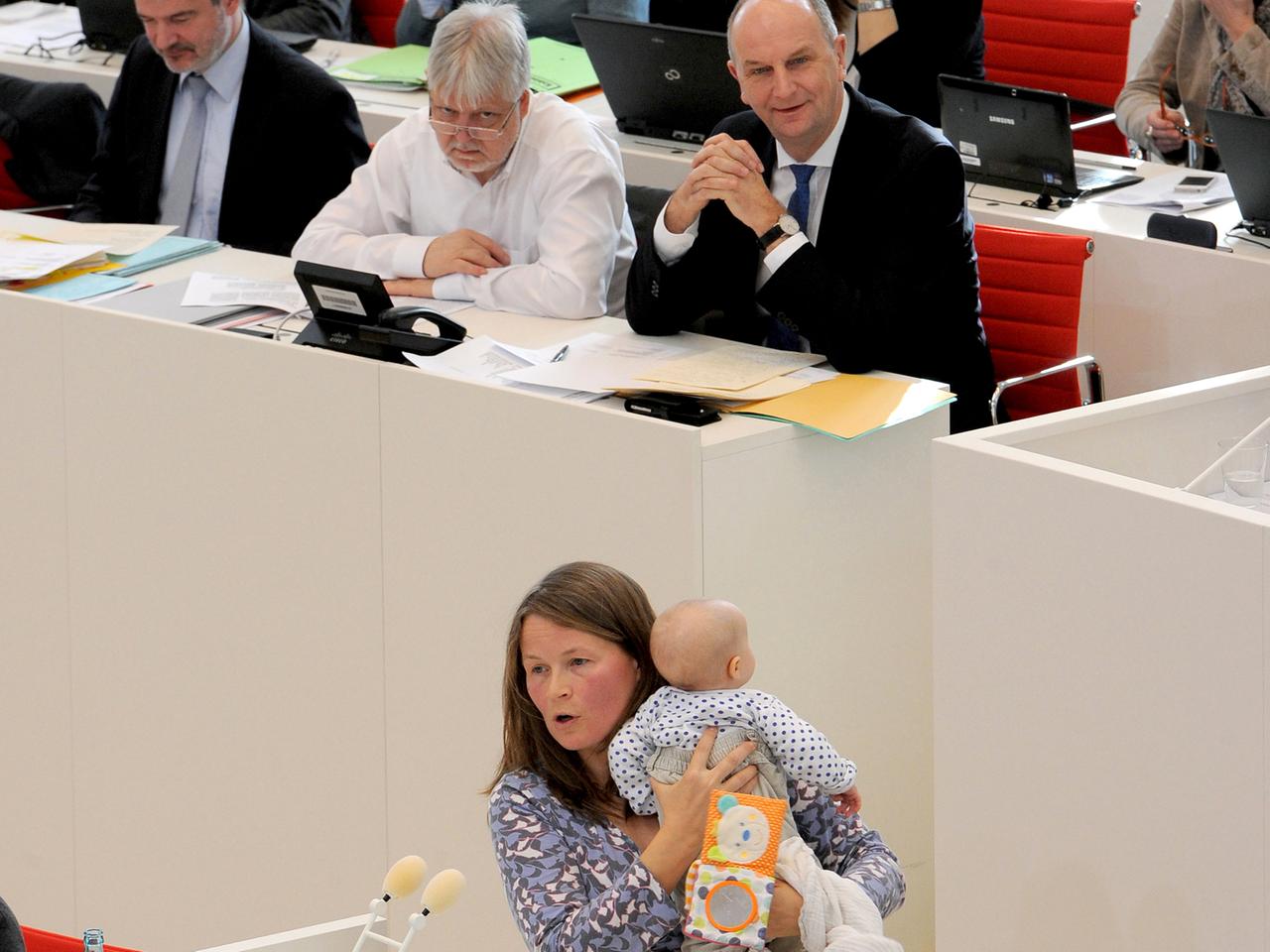 Die Brandenburger Landtagsabgeordnete Sabine Niehls hält eine Rede im Landtag mit ihrem Baby auf dem Arm.
