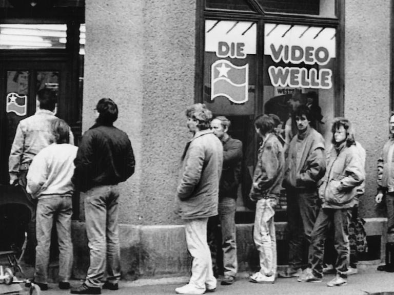 Kunden stehen im März 1990 in einer langen Warteschlange vor einer neueröffneten Videothek in Leipzig.