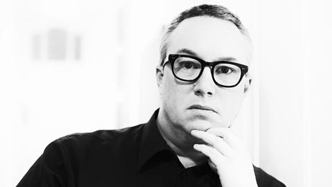 Florian Ross mit schwarzer Brille vor weißem Hintergrund.
