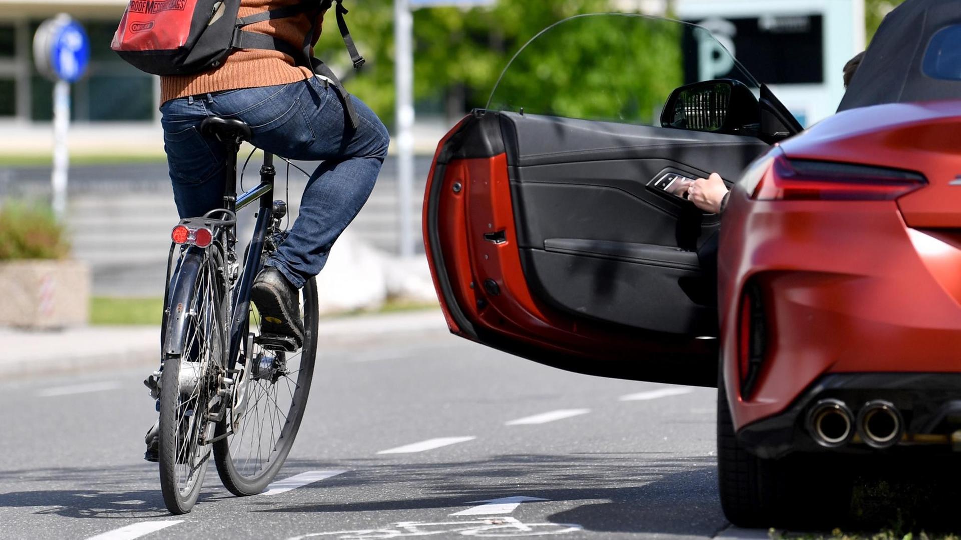 Ein Fahrradfahrer schafft es gerade noch um eine sich öffnende Autotür herum.