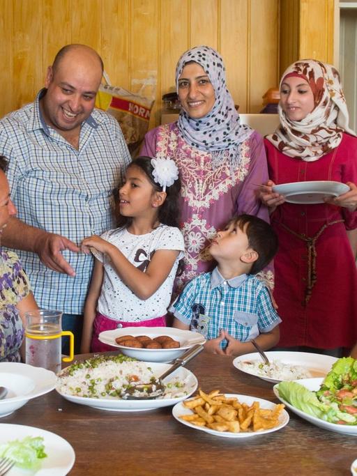 Der Syrer Walid Al Ali (3. v. l.) spricht am 03.08.2016 in Mangolding (Bayern) neben seiner Familie mit Helfern. Der 38-Jährige ist glücklich mit dem Dorfleben in der Oberpfalz.
