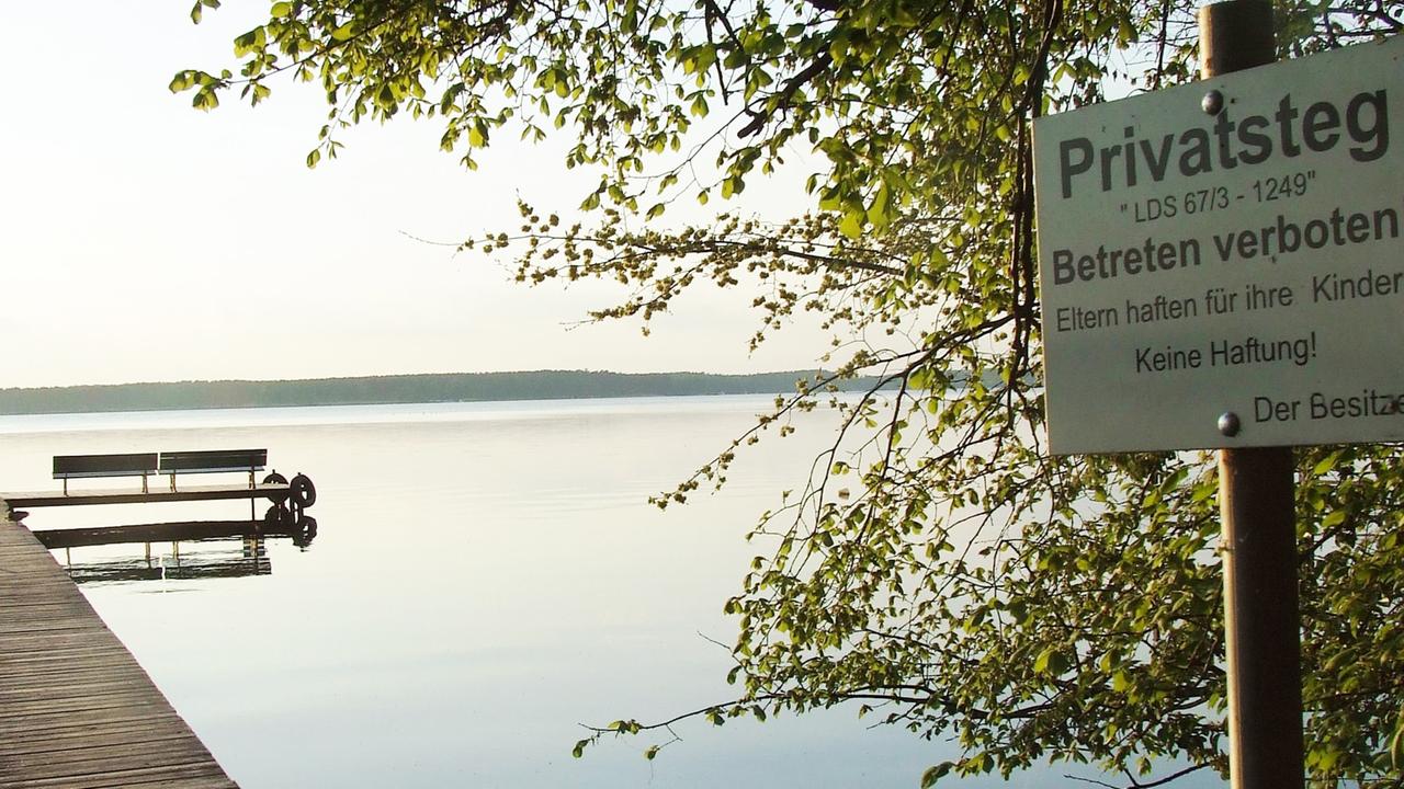 Ein Steg führt auf einen See hinaus. Rechts zu sehen: Ein Schild mit der Aufschrift: "Privatsteg. Betreten verboten!"