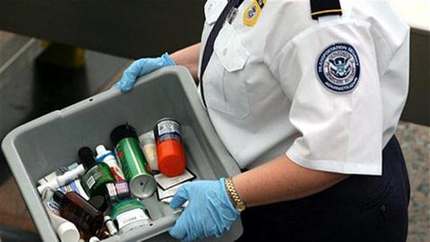 Ein Sicherheitsbeamter trägt einen Behälter mit beschlagnahmten Gegenständen aus den Passagierkontrollen des Flughafens in Denver.