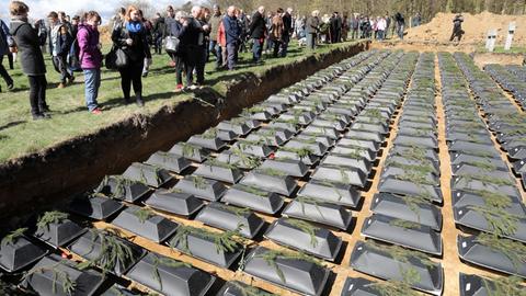 Bei einer Zeremonie des Volksbundes Deutsche Kriegsgräberfürsorge zur Einbettung von 1.800 deutschen Kriegstoten am 06.04.2017 auf der Kriegsgräberstätte Stare Czarnowo (Neumark) in Polen werfen die Gäste rote Nelken auf die Särge.