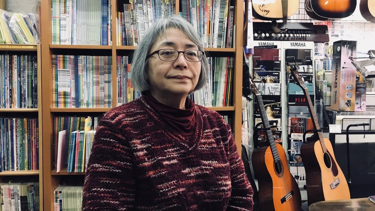 Frau Nikis Vater lernte das Geigenspiel von einem deutschen Kriegsgefangenen im Lager Bando und eröffnete dieses Musikfachgeschäft in der Nachbarstadt Tokushima. Sie steht mitten zwischen Instrumenten.