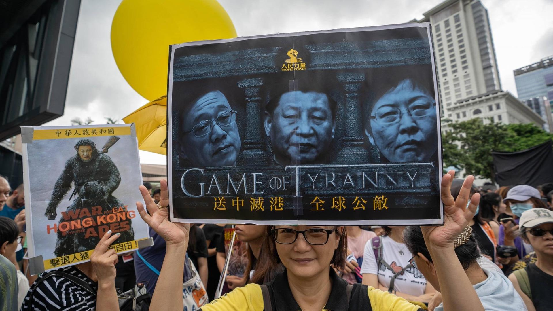Demonstranten in Hongkong halten ein Schild in die Höhe mit dem die lokale Regierung und er chinesische Staatschef Xi Jinping kritisiert werden.