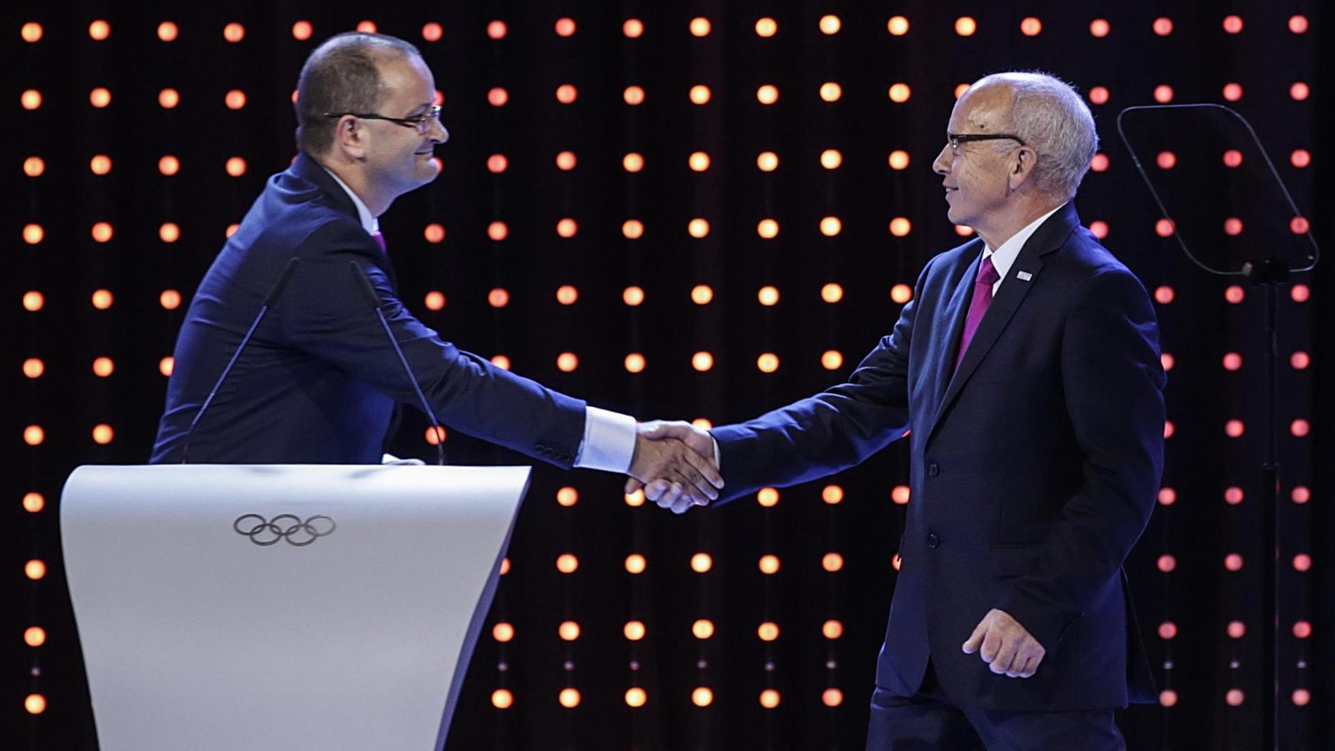 Der jetzige Schatzmeister von SportAccord, Patrick Baumann (l), schüttelt dem Schweizerischen Sportminister Ueli Maurer (r.) während der Präsentation der Kandidatenstädte für die Jugend-Winderspiele 2020 die Hand.