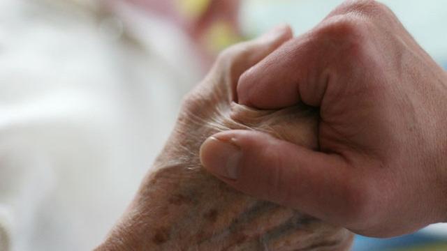 Ein Sanitäter hält die Hand einer Rentnerin
