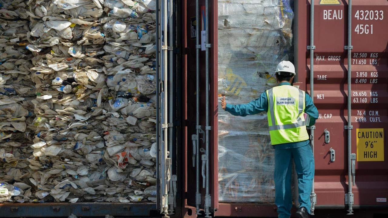 Im Hafen von Port Klang in Malaysia kommt ein Container mit Plastikmüll an. Ein Arbeiter öffnet die Tür.